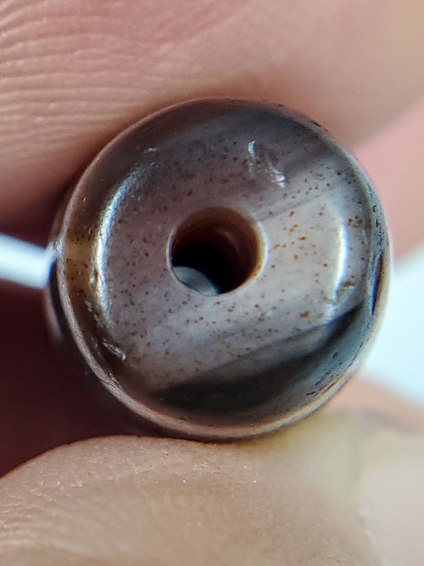 Macro: ancient dzi drill hole end-face — aged brown cap, iron-oxide dots, deep centred drill hole, Anc-0426-2DE
