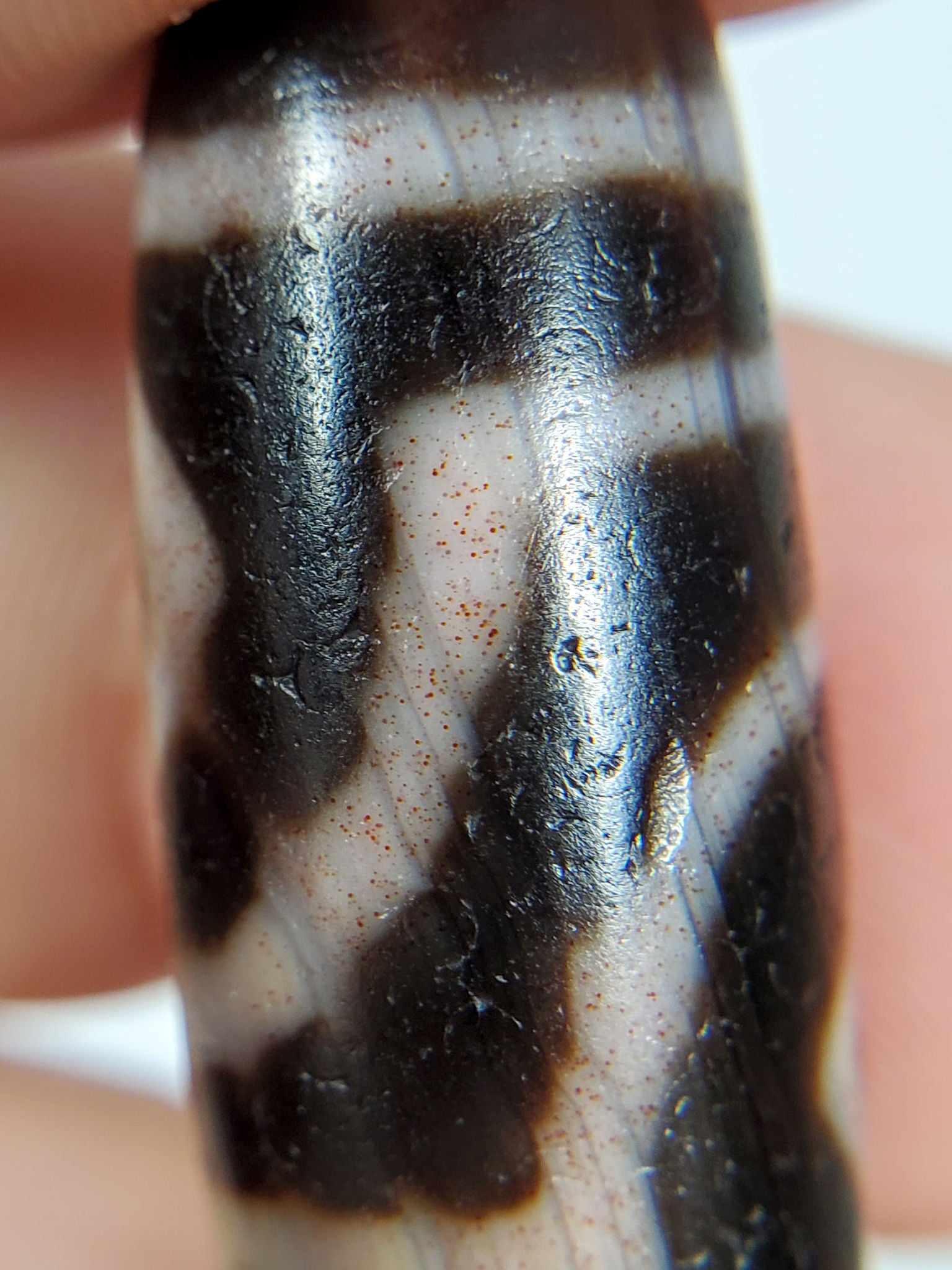 Macro: ancient two diamond eye dzi — white stripe field with scattered red-orange iron-oxide bloodspot dots, Anc-0426-2DE