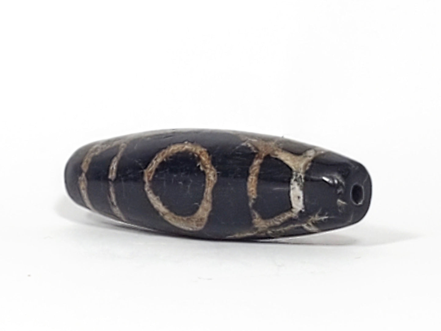 Ac-070926-TWE ancient two eye dzi angled view showing drill end pitch-black end cap both eyes partially visible unretouched