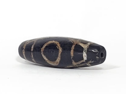 Ac-070926-TWE ancient two eye dzi angled view showing drill end pitch-black end cap both eyes partially visible unretouched