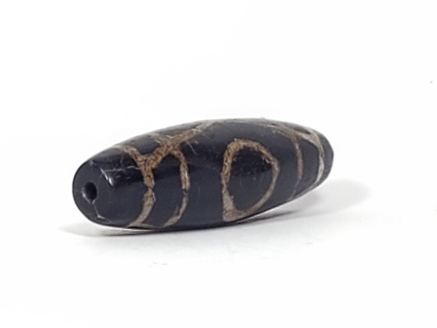 Ac-070926-TWE ancient two eye dzi opposite drill end angled view pitch-black agate heavy calcification unretouched