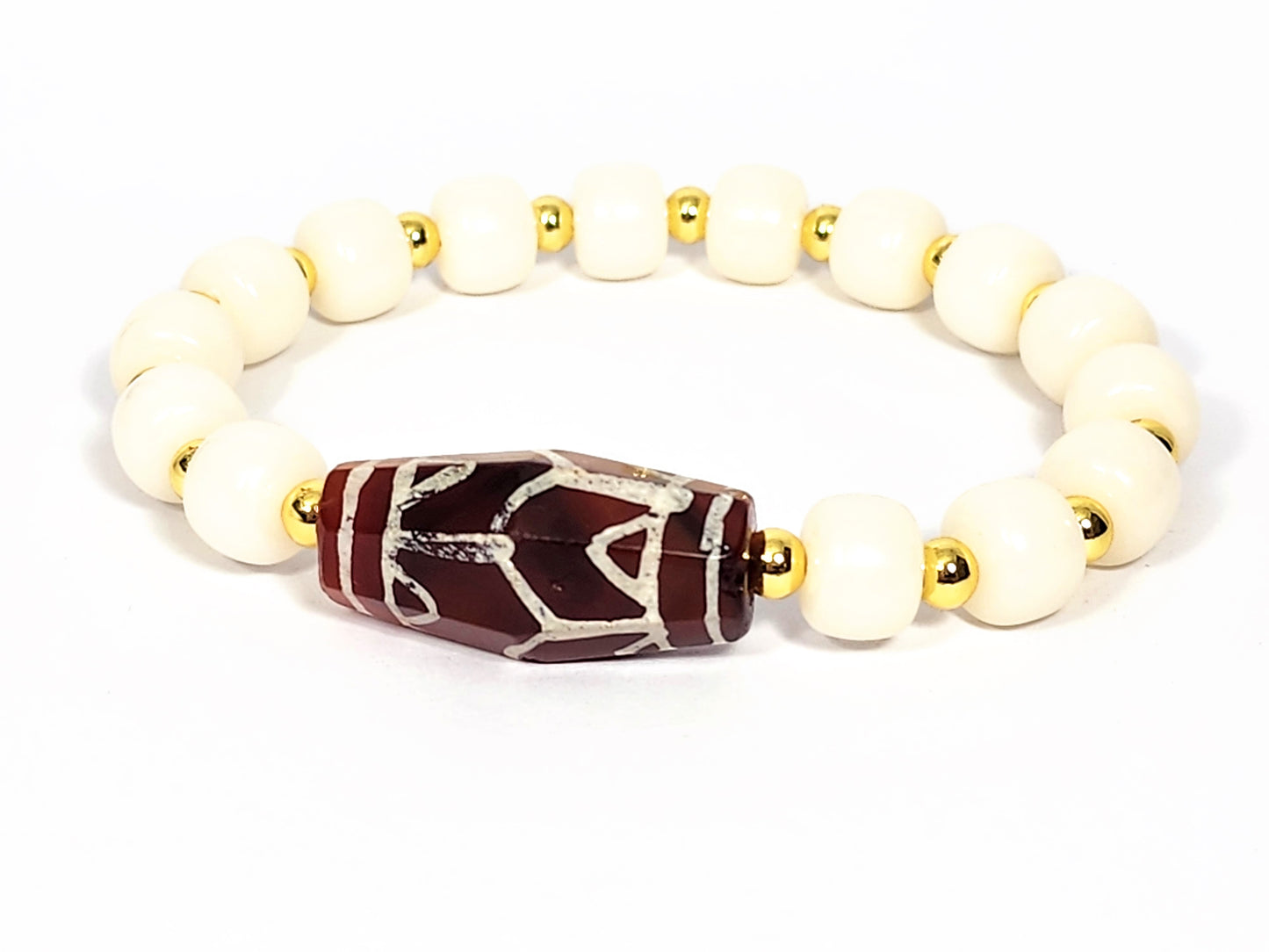 A bracelet with a large Ancient Carnelian focal bead featuring a Lotus & Tiger Tooth Motif, surrounded by smaller White Bodhi Root complement beads.