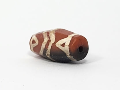 Ac-061126-TSTT angled end, small drill hole, vivid orange-red end cap against grey-black body, motif visible, unretouched