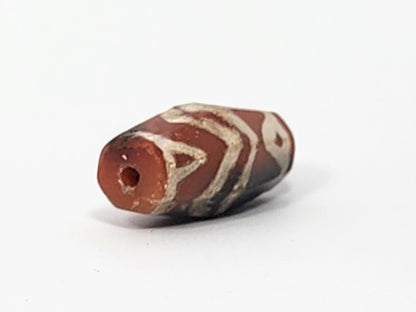 Ac-061126-TSTT opposite end, vivid terracotta-red drill hole face, weathered bore, tiger motif wrapping body, unretouched
