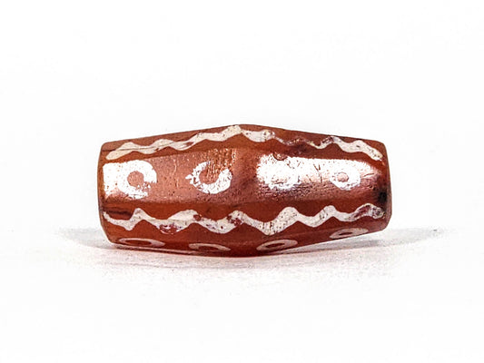 Ac-010825-16EW hero angled, 24.1×11.0mm terracotta-red carnelian, eye rings and wave bands visible, octagonal, unretouched