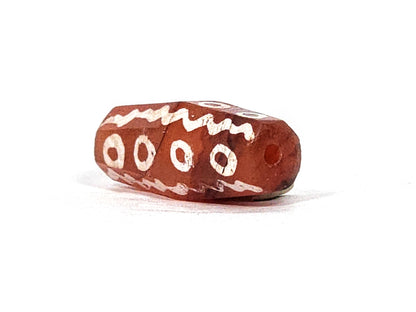 Ac-010825-16EW angled end, drill hole, octagonal facets visible, 4 ring eyes, wave band, terracotta-red, unretouched