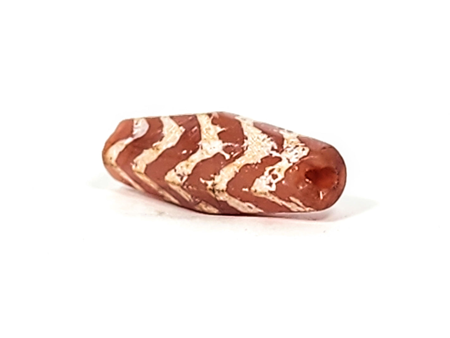 Ac-030525-5TS carnelian dzi End A, tapered terminus, ancient drill hole visible, terracotta-red, unretouched