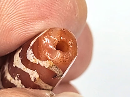 Ac-030525-5TS macro End B, funnel-shaped ancient drill hole, worn rim, warm terracotta carnelian, unretouched