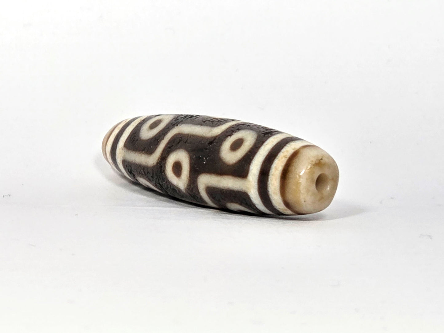 Ac-070926-9E ancient nine eye dzi angled view right drill end warm honey-cream end cap drill hole unretouched