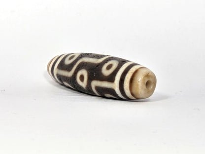 Ac-070926-9E ancient nine eye dzi angled view right drill end warm honey-cream end cap drill hole unretouched