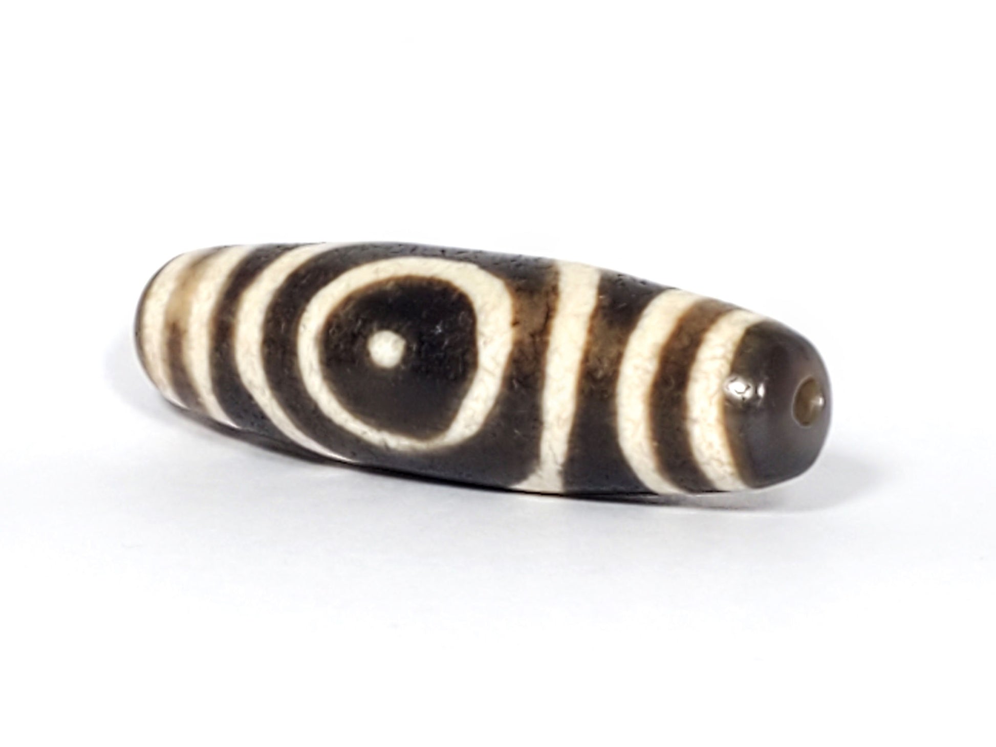 Ac-082325-DHE2 angled view, oval face visible, drill hole right end, honey-tan tip, semi-gloss surface, unretouched
