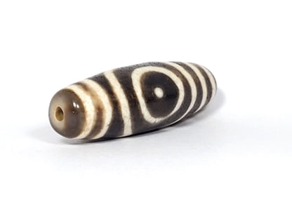 Ac-082325-DHE2 opposite end angled, drill hole left, sandy-brown tip, oval and stripe motif wrapping body, unretouched