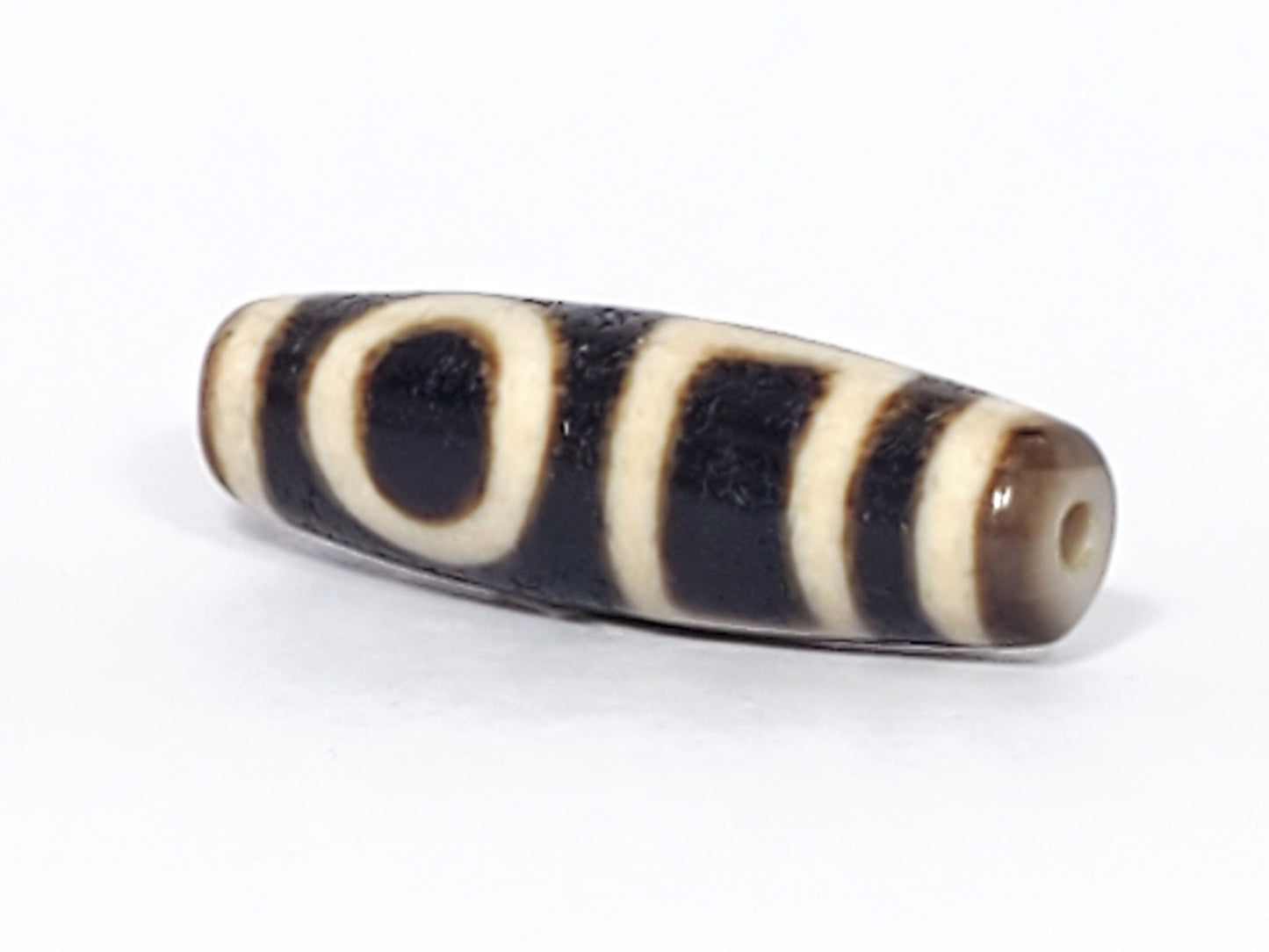 Ac-052523-DHE angled view, drill hole tip right, honey-brown end, pitch-black fusiform body, oval visible, unretouched