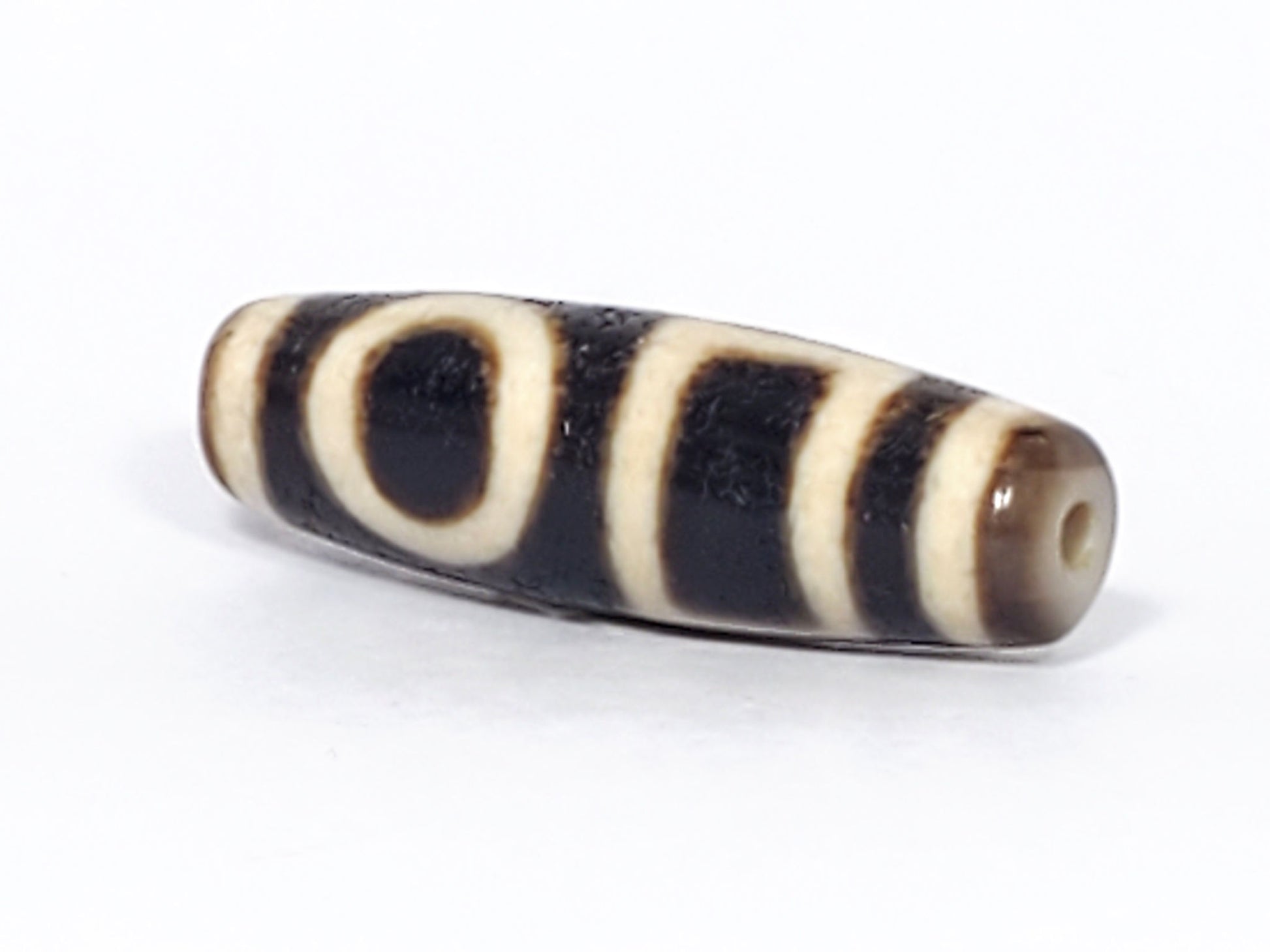 Ac-052523-DHE angled view, drill hole tip right, honey-brown end, pitch-black fusiform body, oval visible, unretouched