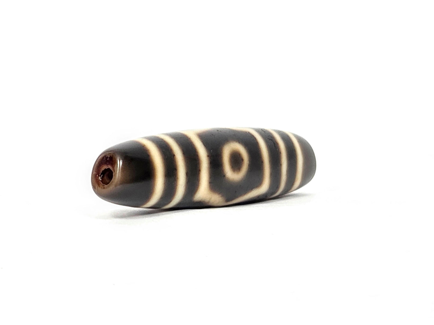 Ac-070926-THE ancient three eye dzi angled view left drill end warm reddish-brown end cap cream motif unretouched