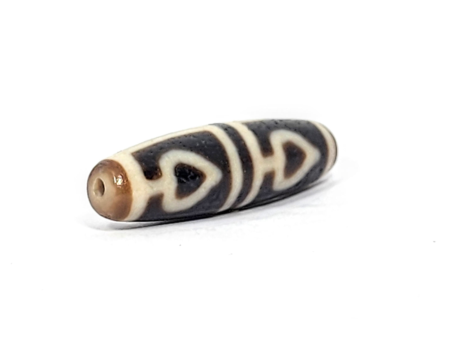 Ac-070625-FLB3 left drill hole end, sandy-tan tip and drill interior, bodhi leaf curves visible from end, unretouched