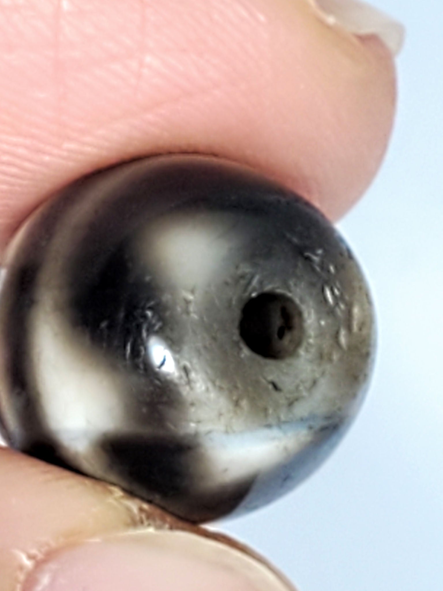 Ac-021724-TT ancient round tiger tooth dzi, macro drill end view, micro-pitting detail, unretouched