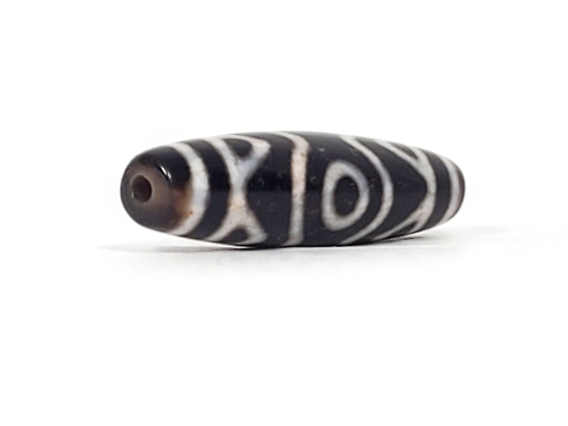 At-070926-3ETTBS antique three eye tiger tooth dzi angled view left drill end pitch-black body profile unretouched