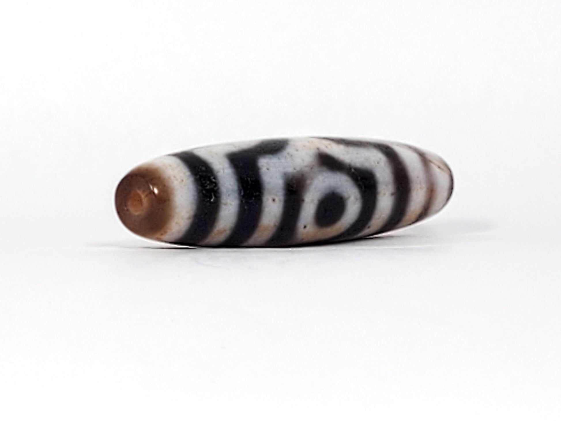 Fifth angle of antique Tibetan Three Eye Dzi bead — deep black agate with bold white etching, extreme cinnabar inclusions, 100–200 years old