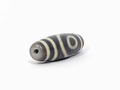 Ac-052525-2E left drill hole end, cool grey-brown tip, concentric ring eye visible from end angle, unretouched
