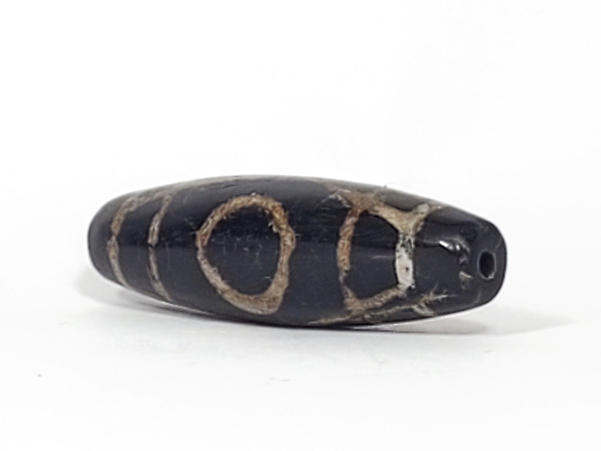 Ac-070926-TWE ancient two eye dzi angled view showing drill end pitch-black end cap both eyes partially visible unretouched