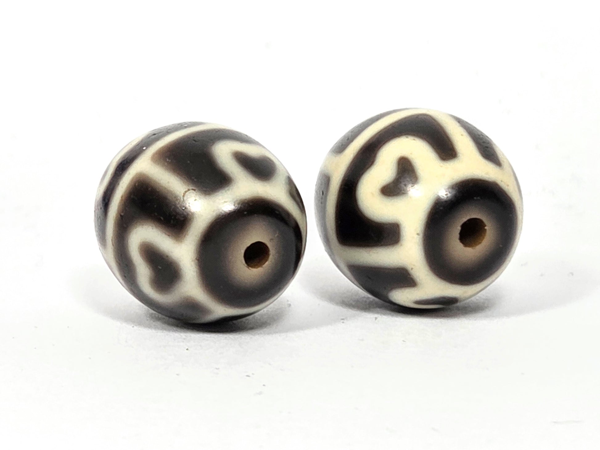 Close up photo showing the drill holes on this pair of six eye lotus antique tibetan dzi beads