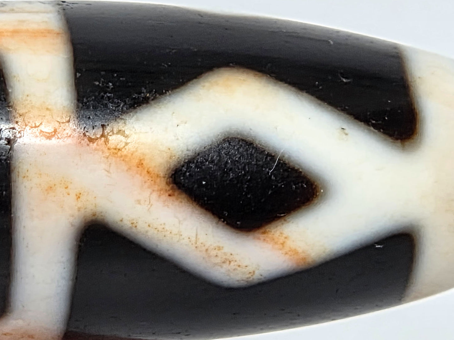 At-062126-6DE dzi bead, macro view of cinnabar dots tracing diamond eye boundary, unretouched