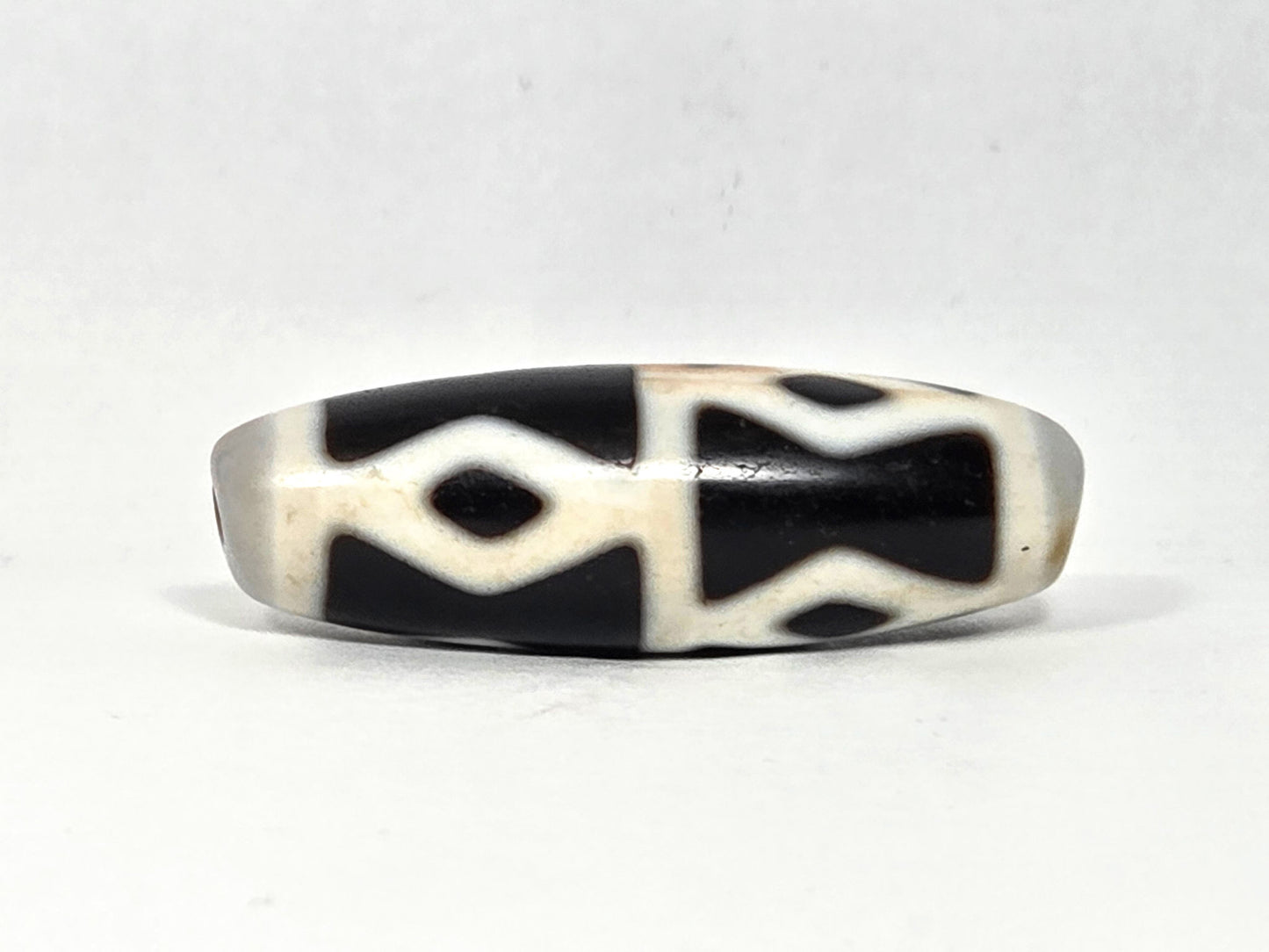 At-062126-6DE dzi bead, angled side profile, black ground and white dividers, unretouched