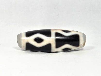 At-062126-6DE dzi bead, angled side profile, black ground and white dividers, unretouched