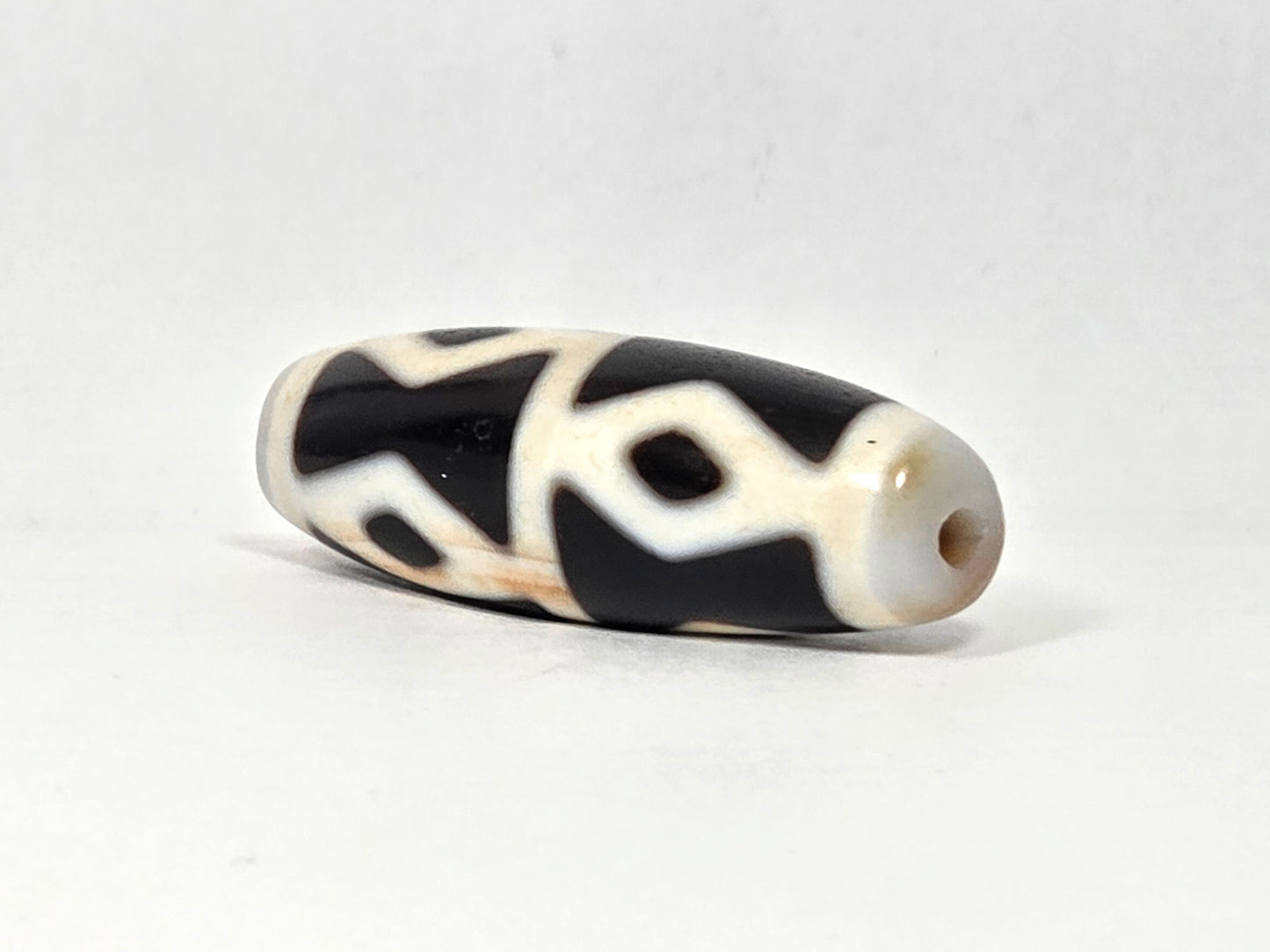 At-062126-6DE dzi bead, end view showing clean drill hole, unretouched