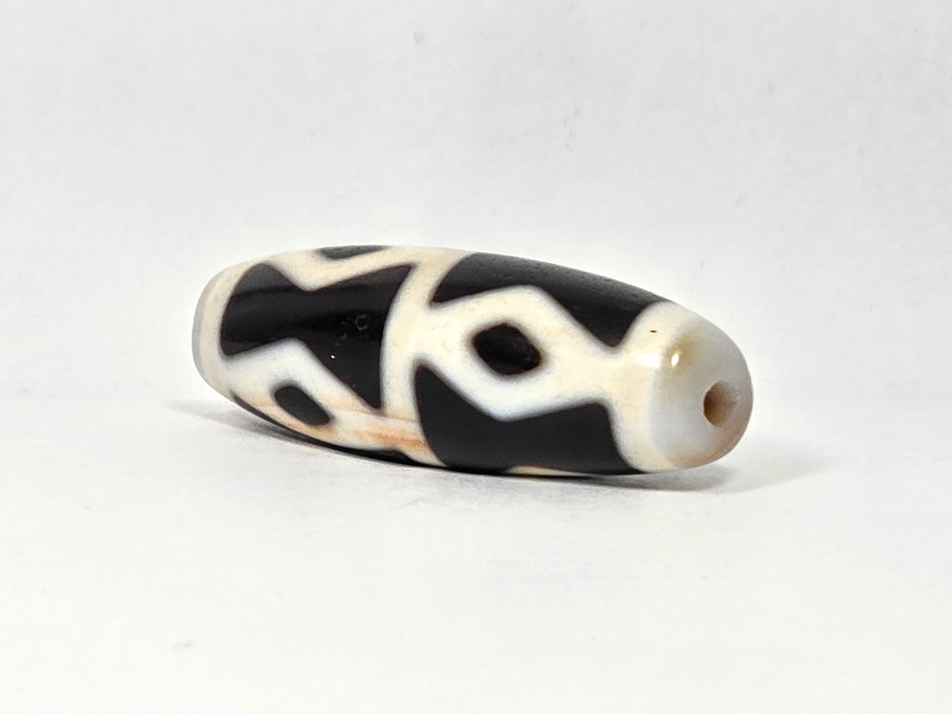 At-062126-6DE dzi bead, end view showing clean drill hole, unretouched