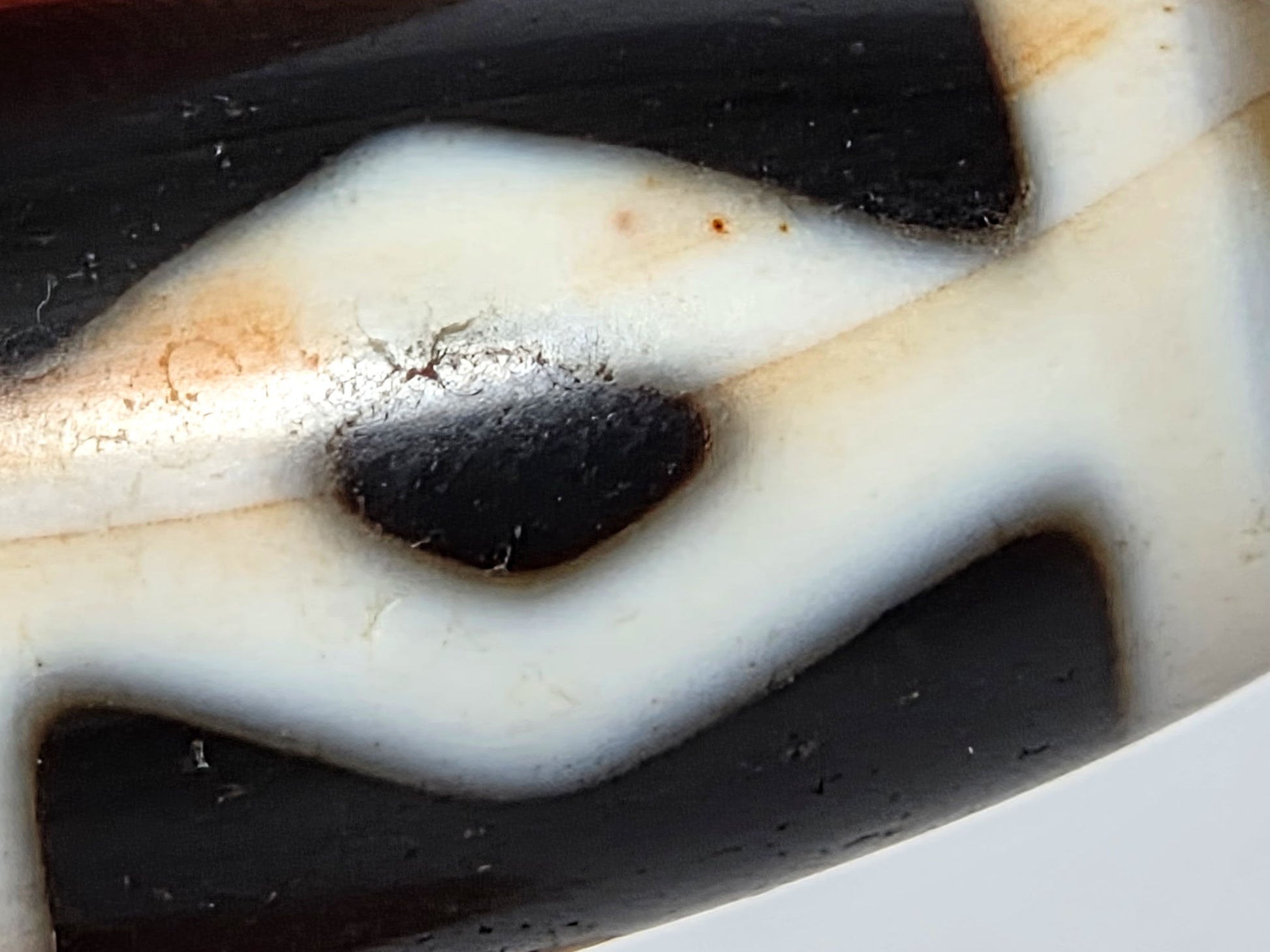 At-062126-6DE dzi bead, macro view of boundary-concentrated cinnabar near diamond edge, unretouched