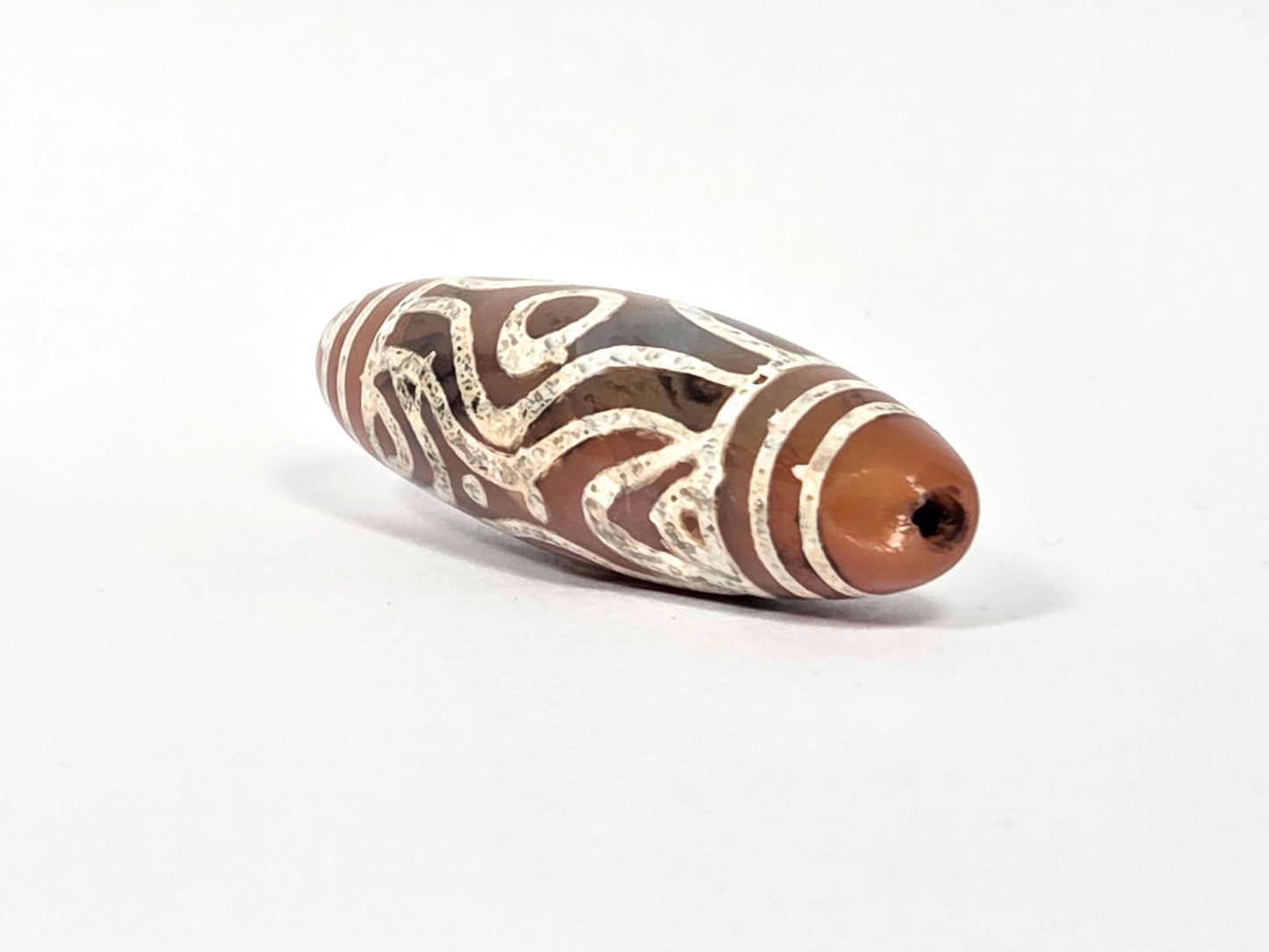 At-061426-2ETTSt carnelian dzi, RIGHT END CHIP DISCLOSED — concave impact chip at tip, drill hole intact, unretouched