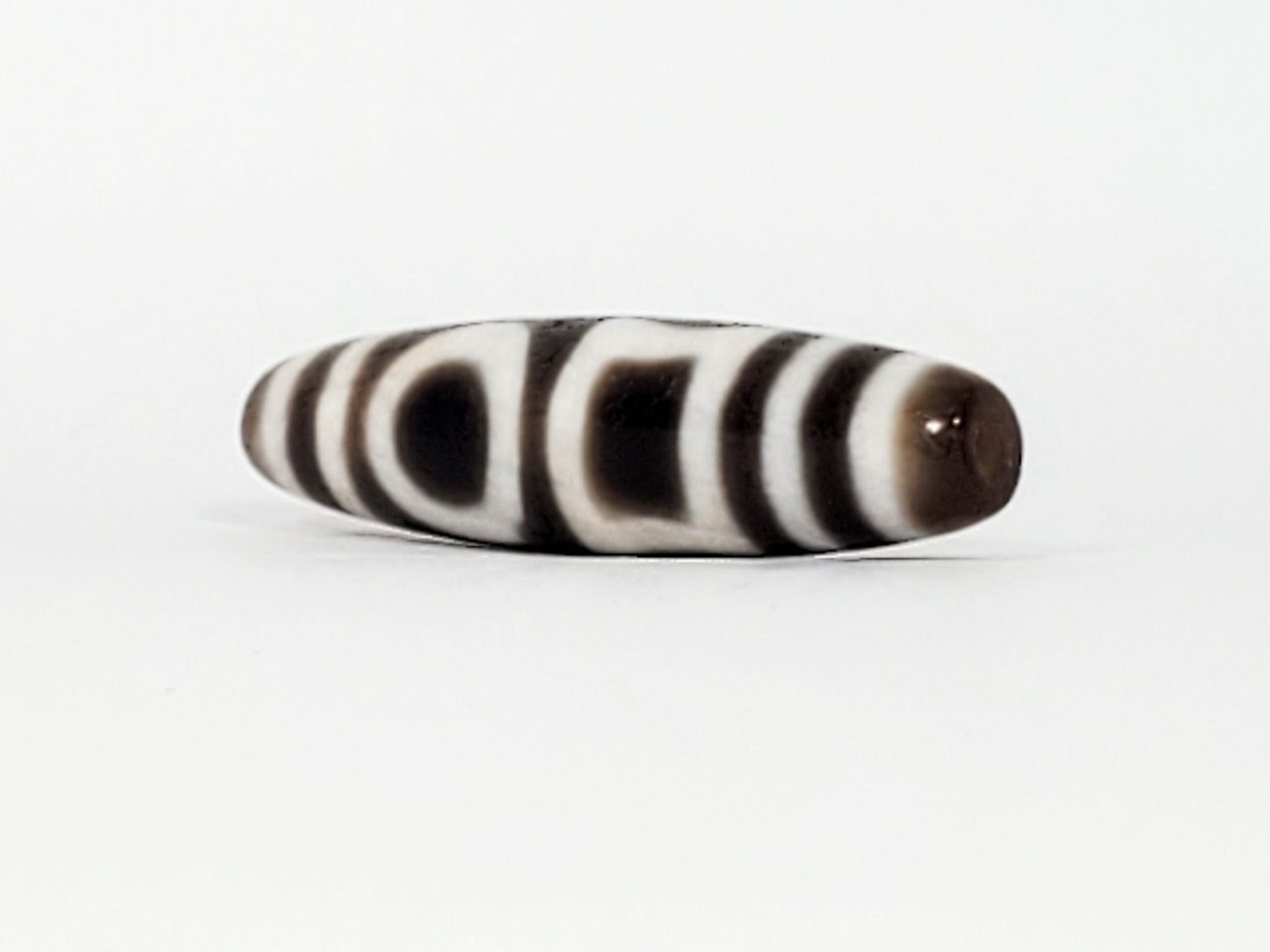 Angled end of antique Double H&E Dzi — drill hole, stripe bands wrapping to tip, tapered profile