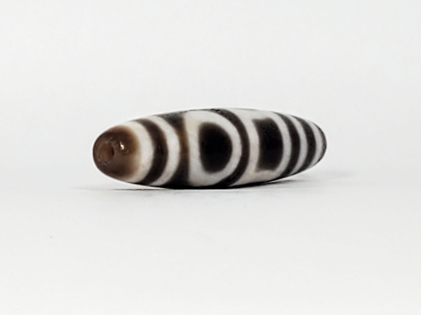 End view of antique Double Heaven & Earth Dzi — drill hole, horizontal stripe bands, warm brown tip