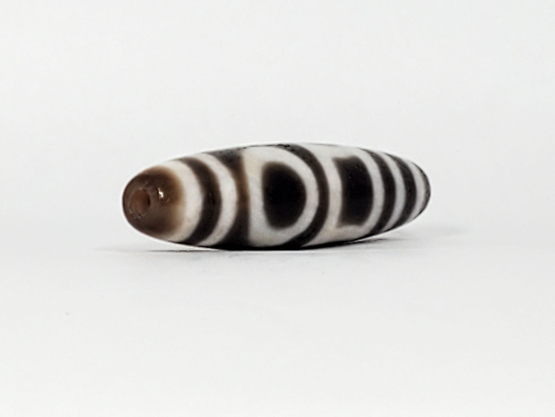 End view of antique Double Heaven & Earth Dzi — drill hole, horizontal stripe bands, warm brown tip