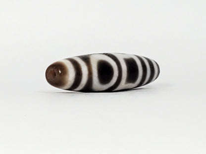 End view of antique Double Heaven & Earth Dzi — drill hole, horizontal stripe bands, warm brown tip