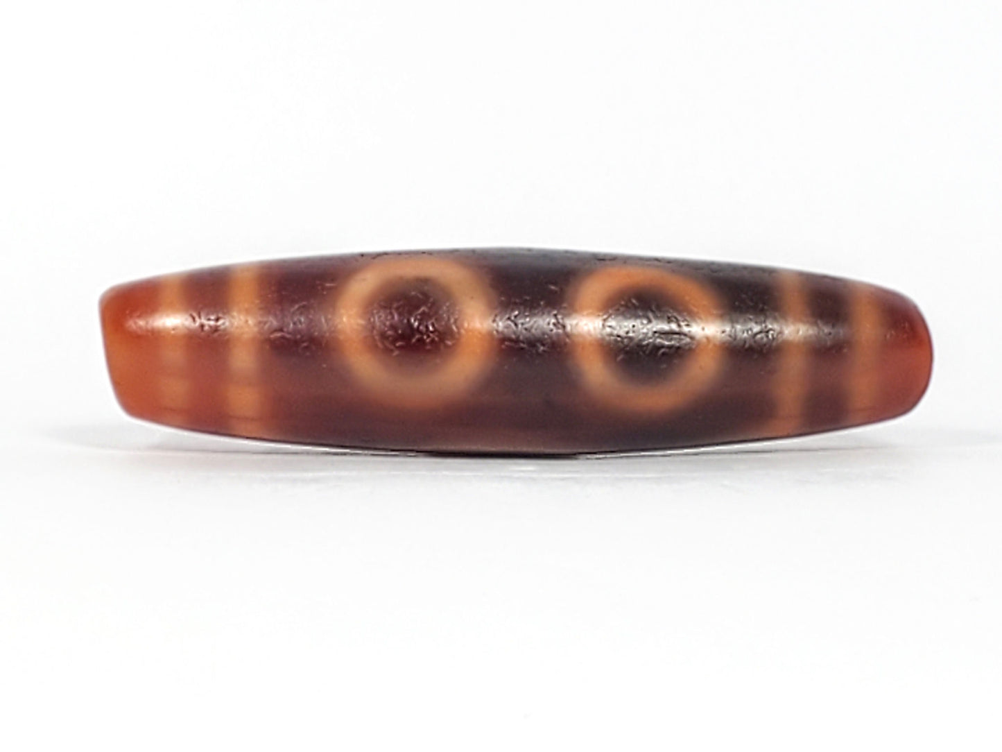 At-060126-4E2, antique four eye dzi 57.1×14.4mm, terracotta-orange and dark-brown agate, open C-ring eyes, unretouched