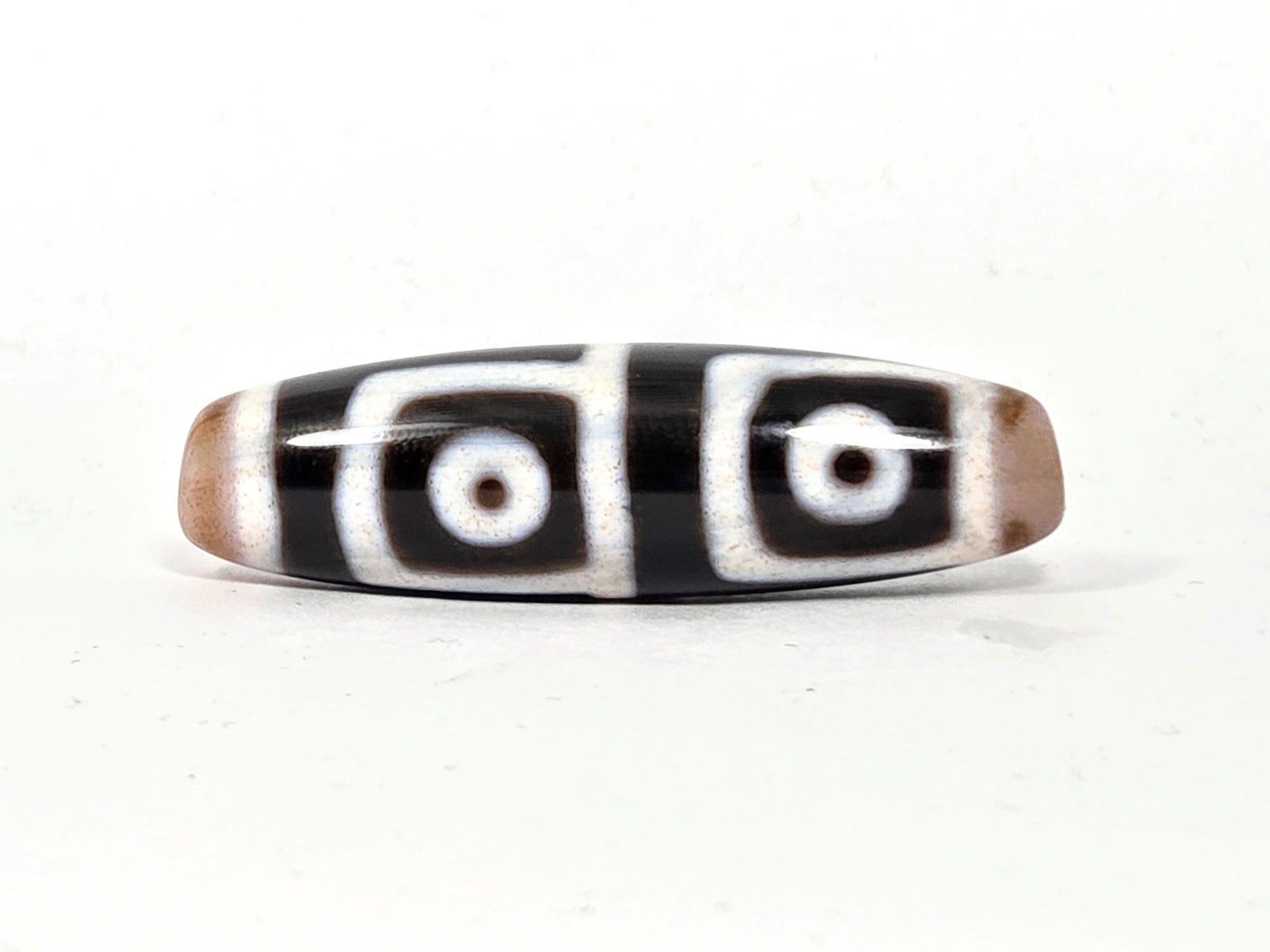 At-042626-4E3 antique four eye dzi, pitch-black ground, white square-framed eyes, 47.5×13.6mm, unretouched