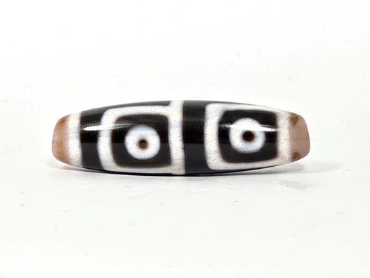 At-042626-4E3 antique four eye dzi, pitch-black ground, white square-framed eyes, 47.5×13.6mm, unretouched
