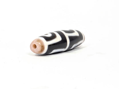 At-042626-4E3 End B, warm sandy-tan end cap, clean drill hole, pitch-black body with white motif, unretouched