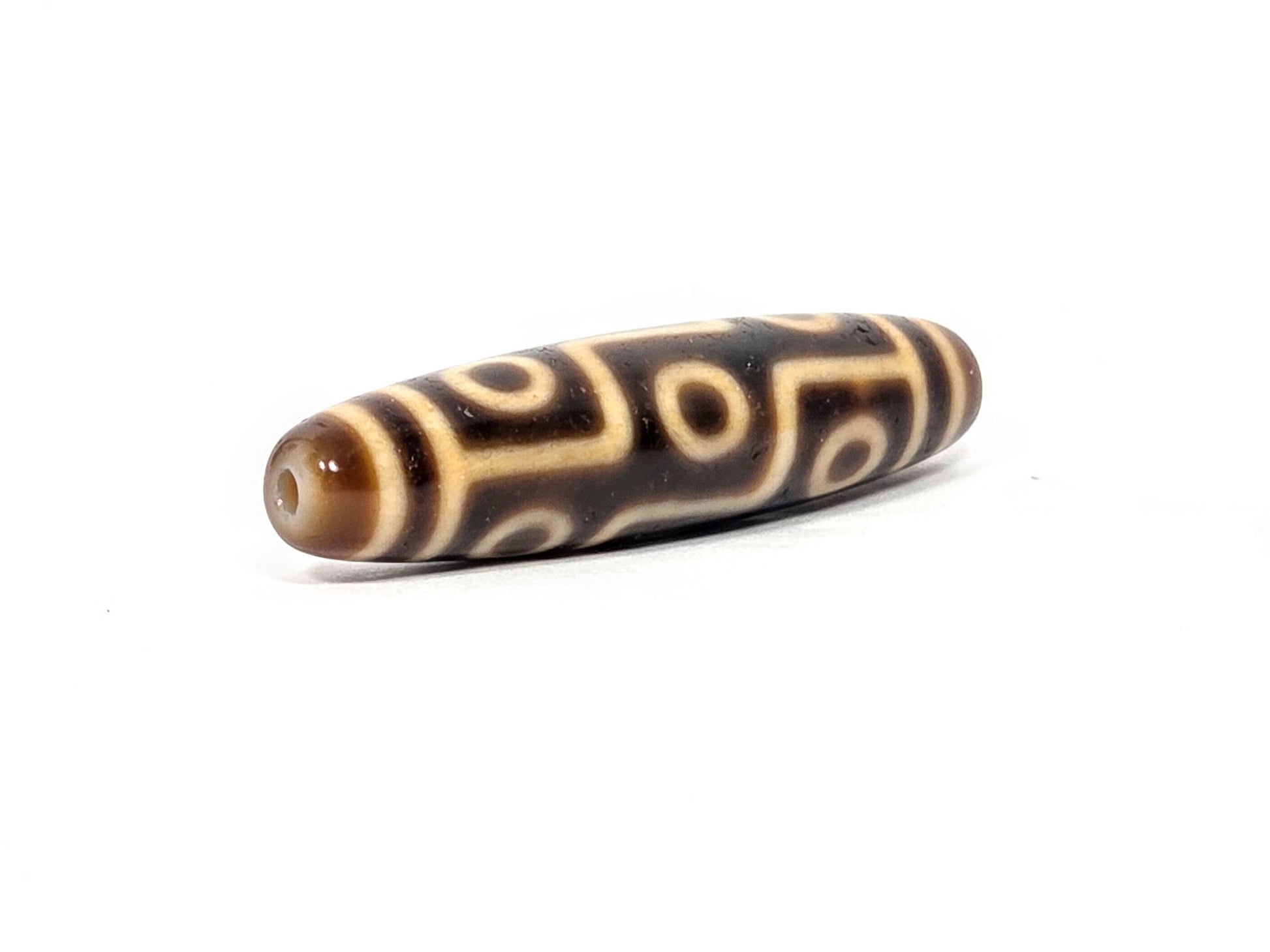 Opposite end of antique Tibetan Nine Eye dzi bead showing polished dark brown dome end cap and eye network, At-083025-9E3
