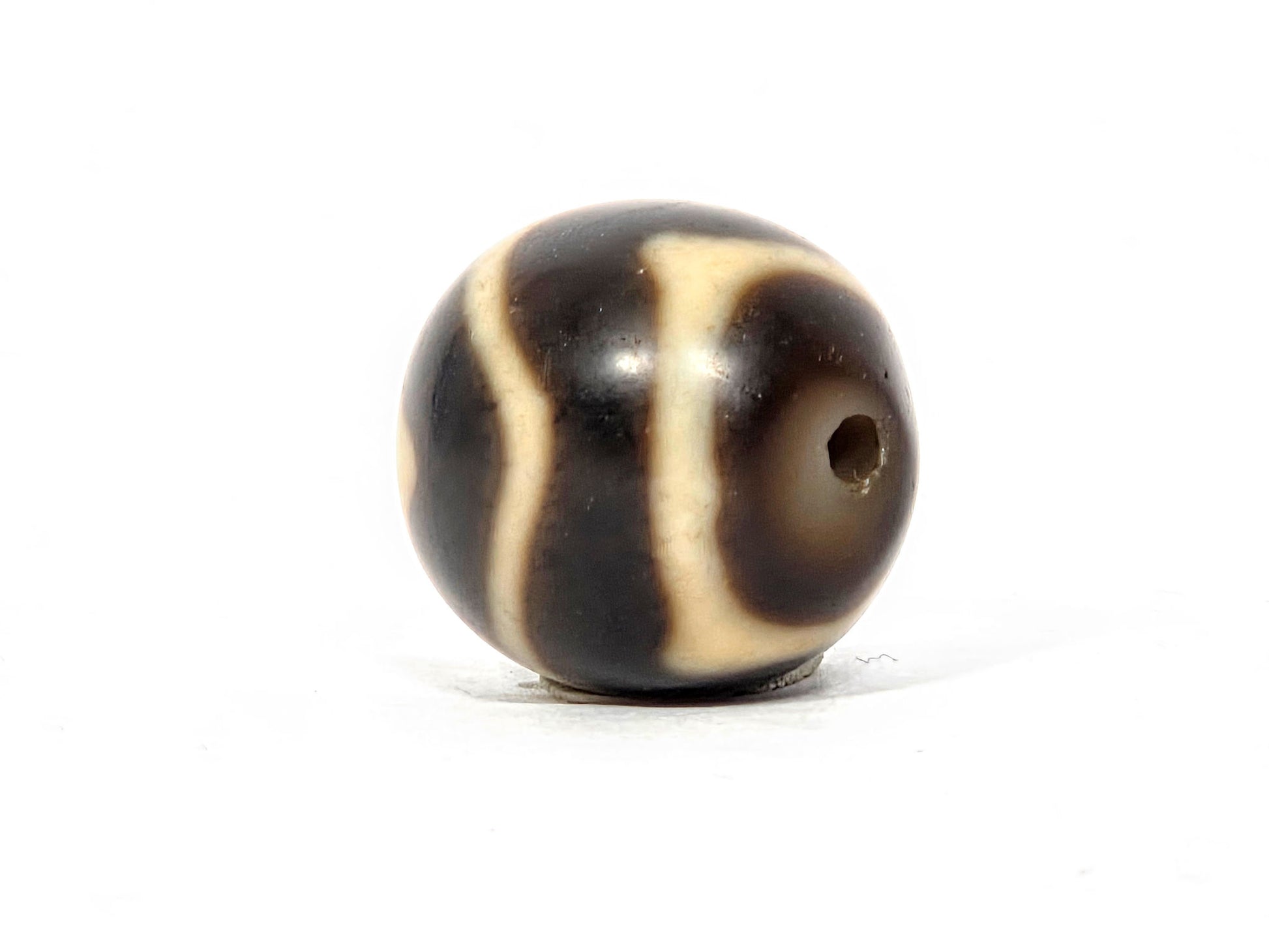 At-111325-WTT antique round wave tiger tooth dzi, drill end view, chocolate-brown end cap, hole centred, unretouched