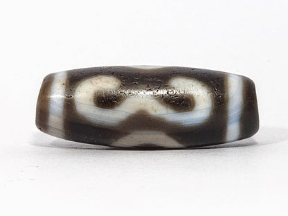 Antique Double Bat Two Eye dzi At-060725-DB2E2, Face A, broad cream double bat wing forms on graphite grey-brown agate, bat pupils visible, 31.5mm × 11.6mm, unretouched