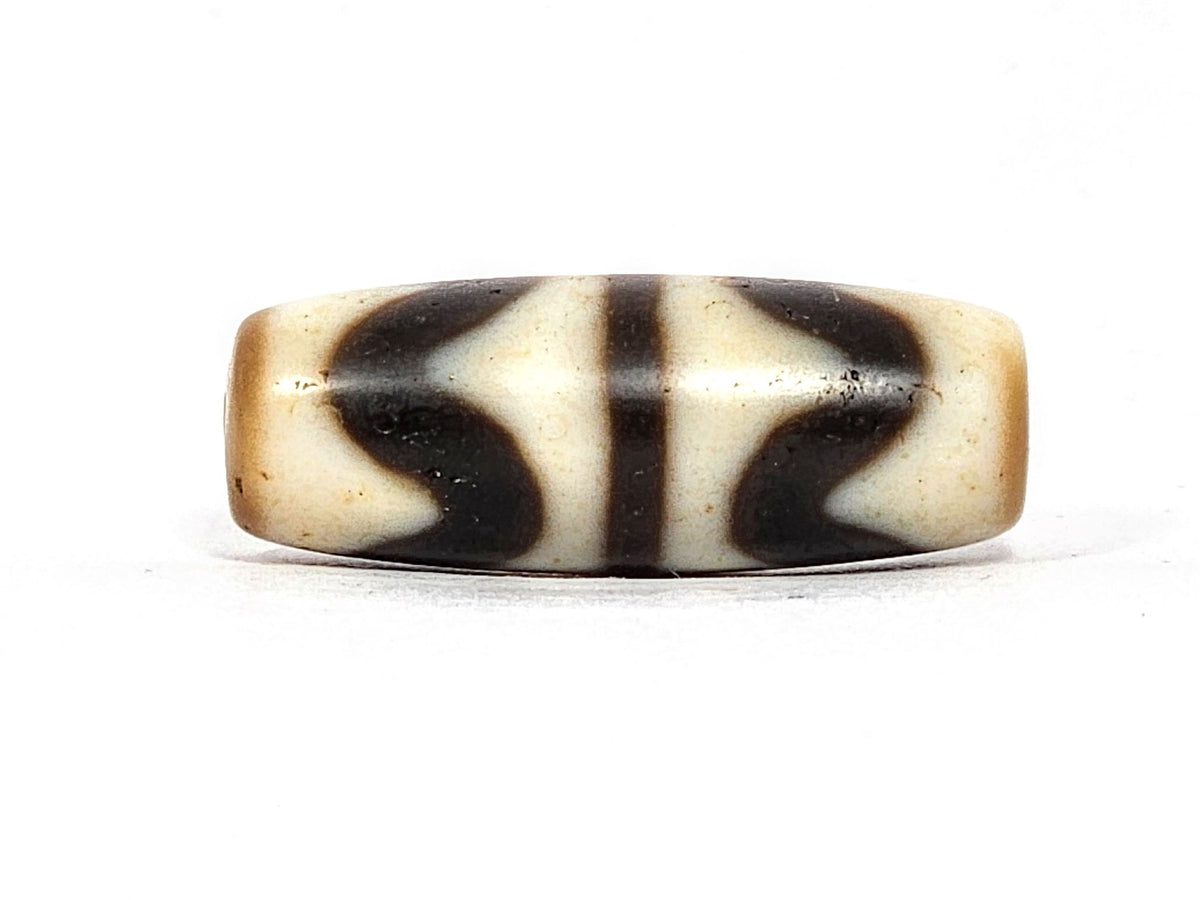 Antique Double Wave dzi bead At-072325-DW5, front face showing two interlocking S-curve waves in cream on warm brown agate, compact 28.4mm × 10.6mm torpedo, unretouched