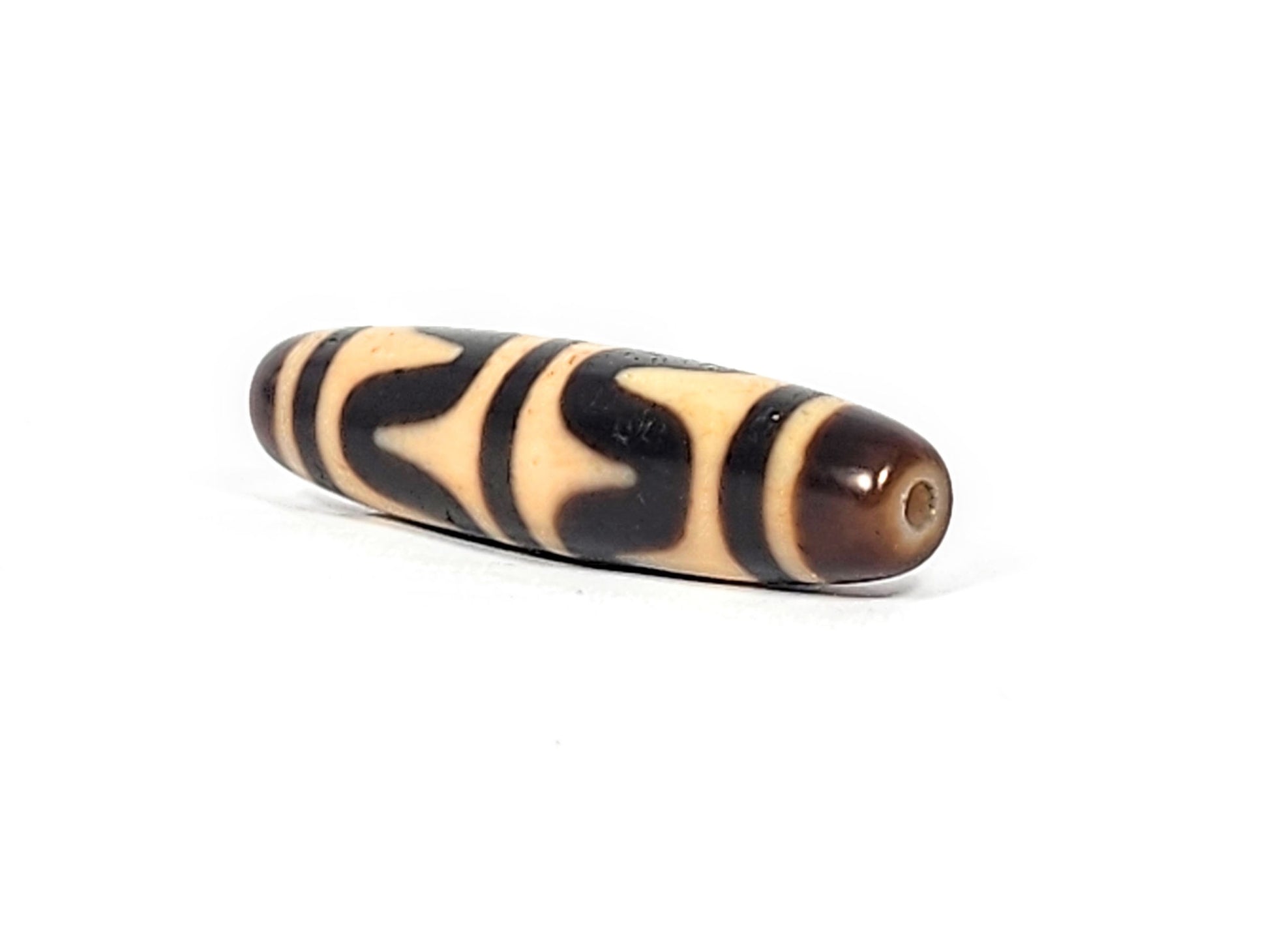 Angled end view of antique Double Wave dzi bead showing dark brown agate end cap and drill hole, At-052526-DW3
