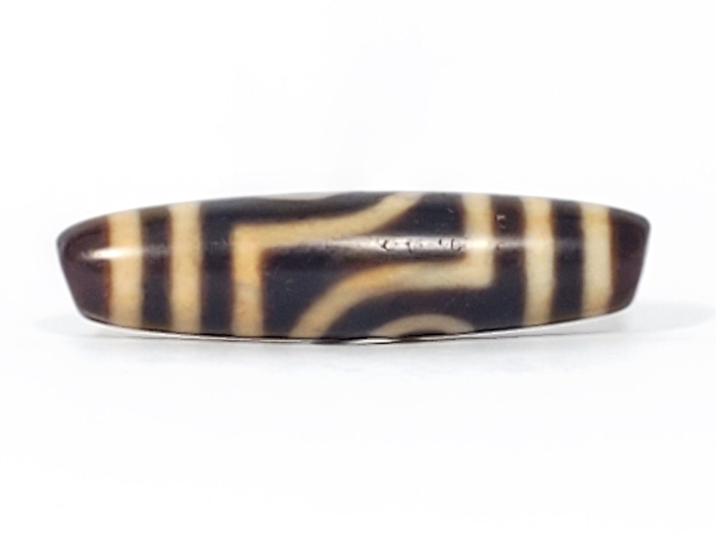 Front face of antique two eye dzi bead At-052526-2E2, open-ring eye left of center with four vertical stripes right, near-black natural agate, 47.4mm × 11.8mm