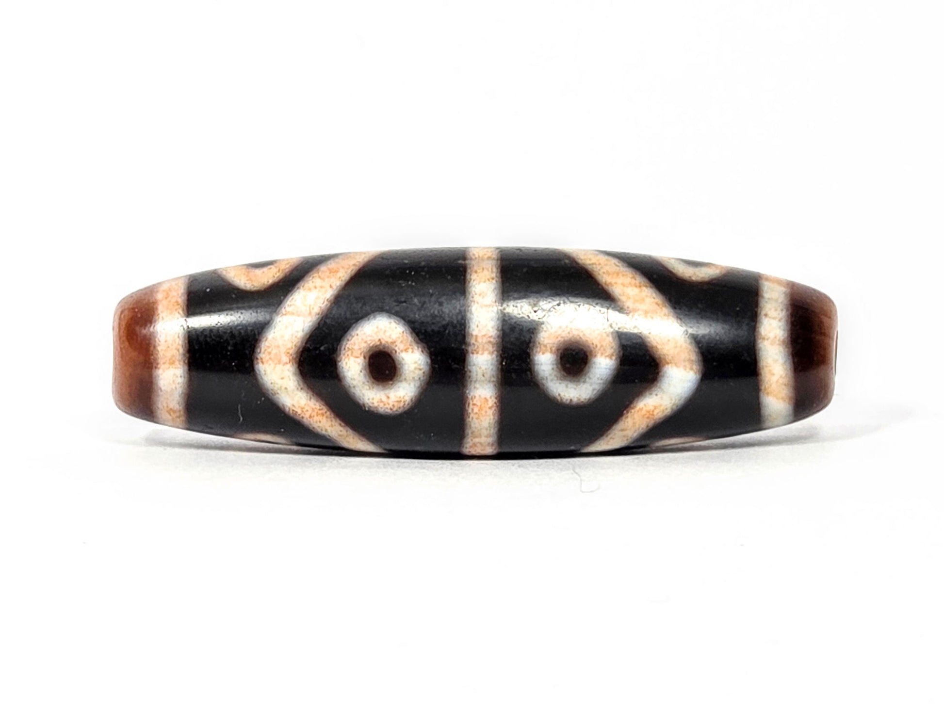 Second face of antique Eight Eye Tiger Tooth Dzi — four eye circles and chevron forms, warm amber tone	102 