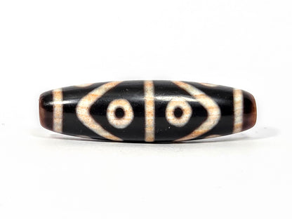 Fourth face of antique Eight Eye Tiger Tooth Dzi — eye circles, tiger tooth forms, warm brown ends