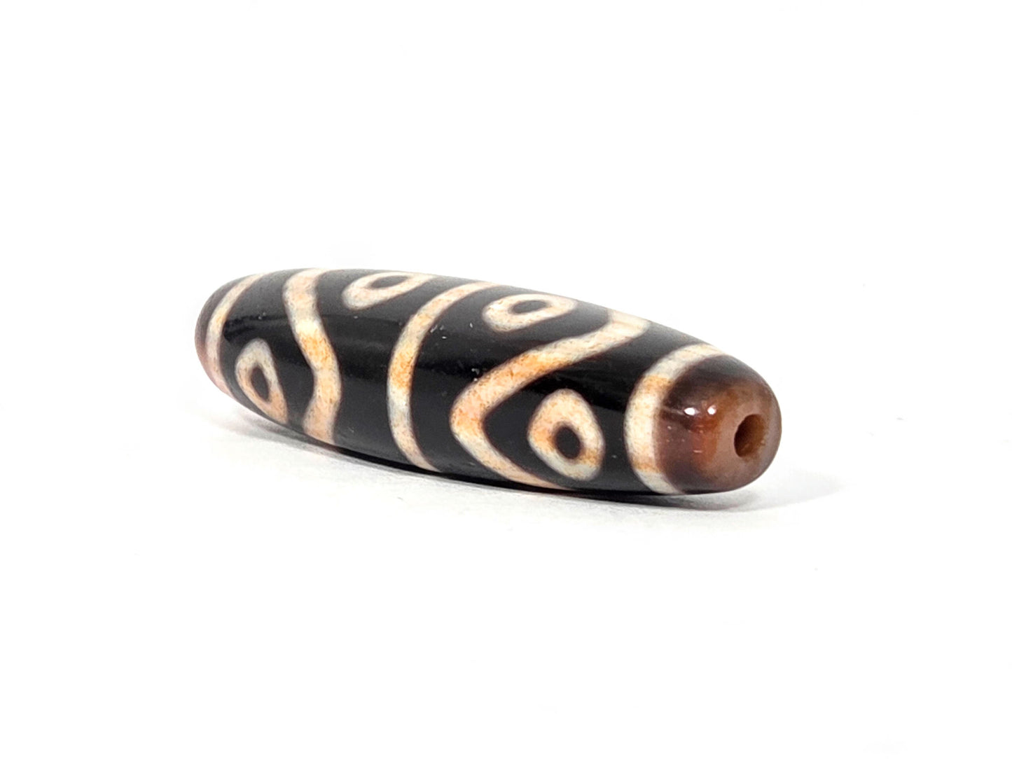 Second end of antique Eight Eye Tiger Tooth Dzi — drill hole, warm amber agate, eye circles wrapping end